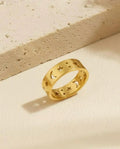 Gold ring with star and moon designs on a beige surface
